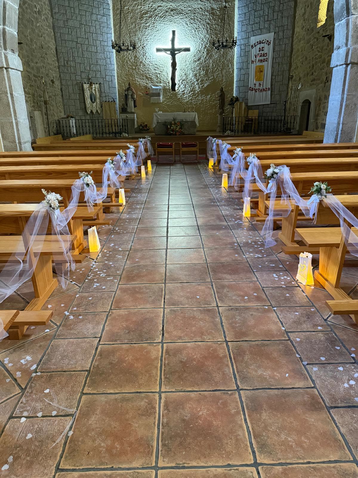 Pasillo de iglesia decorado con flores, tul y farolillos