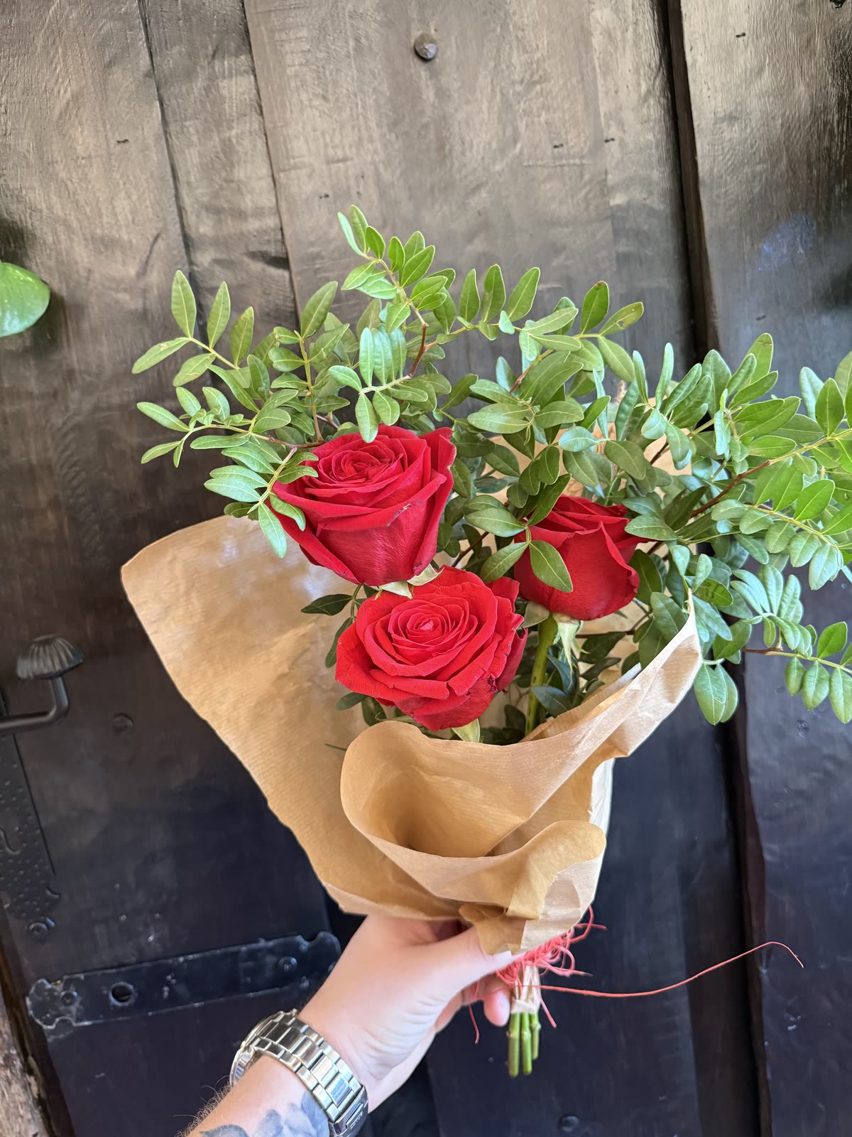 Ramo de tres rosas rojas en papel kraft
